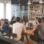 A group of people engaged in discussion at a restaurant table, exploring knowledge management tools